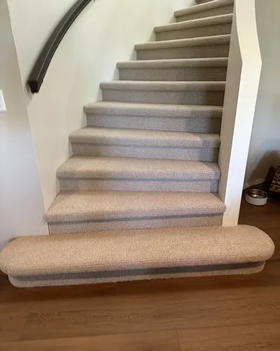 Berber carpet on a curved staircase with a rounded bottom step