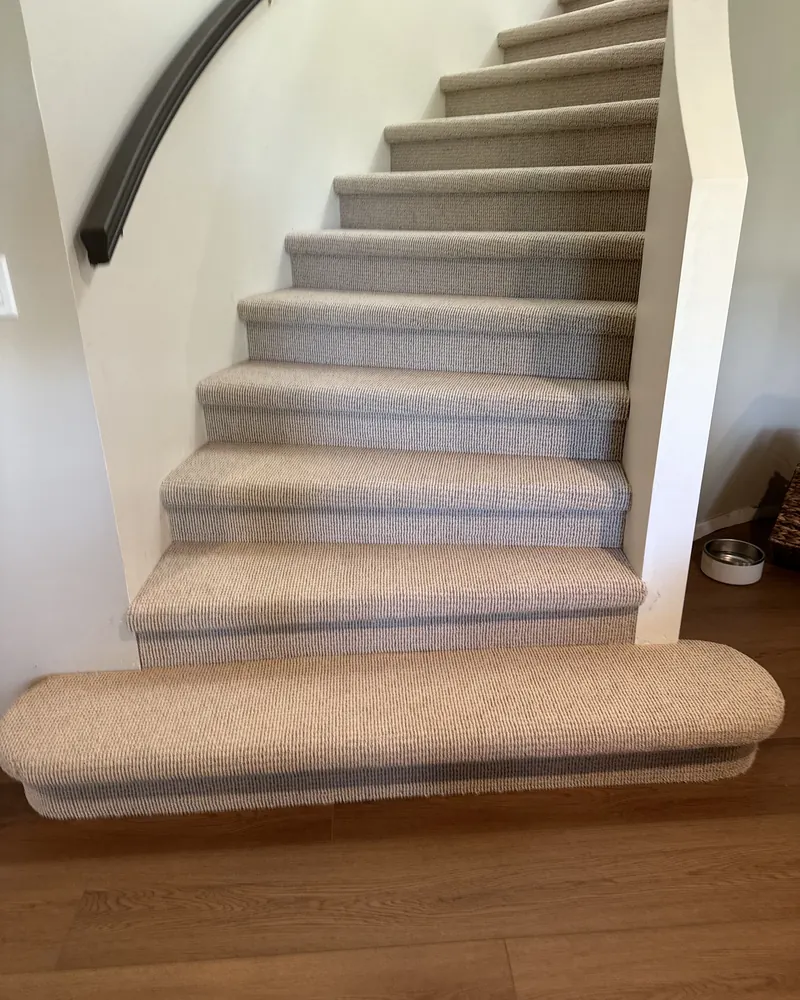 Berber carpet on a curved staircase with a rounded bottom step